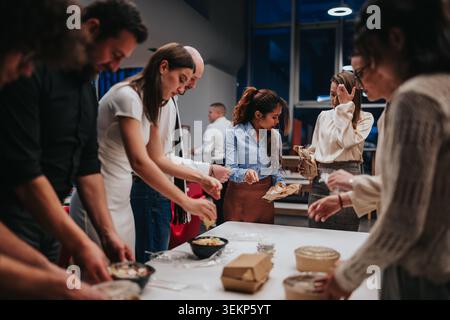 Office coworkers sharing lunch and snacks during a casual team break in a modern workplace Stock Photo