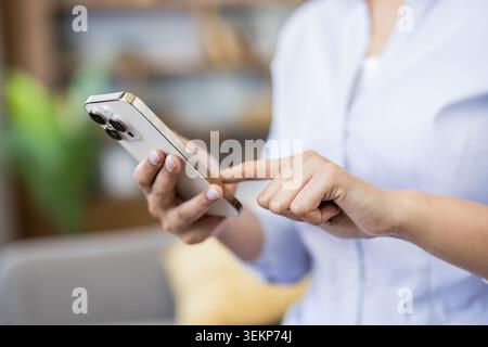 Woman hands holding a modern white smartphone, using touch screen technology for communication, connectivity, and social networking with a blurred background Stock Photo