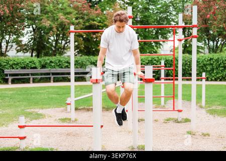Fit man doing dips at a public outdoor gym. Enjoying an active lifestyle, bodyweight training, strength exercise, and healthy habits. High quality pho Stock Photo