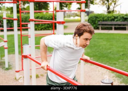 Man doing dips at an outdoor sports ground. Active lifestyle, bodyweight training, functional fitness, and body care. High quality photo Stock Photo