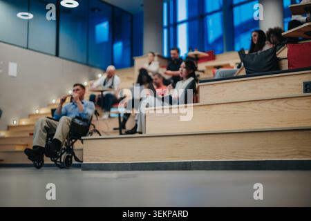 Diverse students and a wheelchair user attending a casual university lecture in modern tiered seating Stock Photo