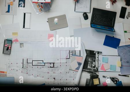 Business team reviewing architectural blueprints and project plans at a collaborative office workspace Stock Photo