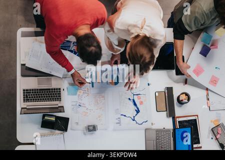 Business team collaborating over maps and charts during a planning meeting in a modern office Stock Photo