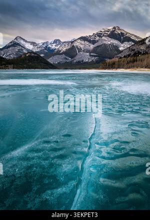 Frozen Abraham Lake in winter with trapped methane bubbles under a dramatic mountain background Stock Photo