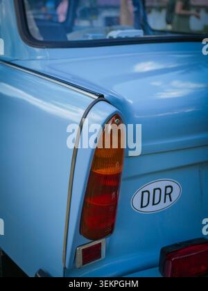 Close-up of a light-blue vehicle's rear quarter panel showing a vertical taillight and DDR badge. Focus on paint quality and body contours. Stock Photo