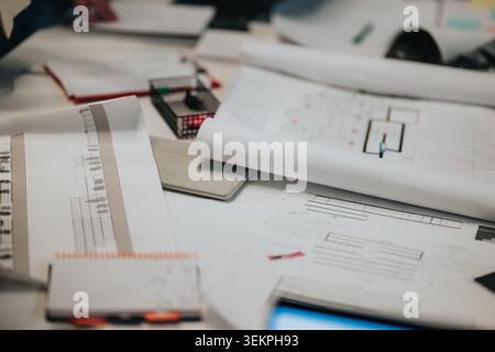 Business workspace with architectural plans and drawings spread across a collaborative office desk Stock Photo