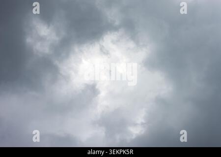 A dramatic and moody view of dark, overcast storm clouds gathering in the sky, with a slightly brighter center Stock Photo