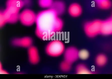 An abstract, out-of-focus bokeh background filled with vibrant, glowing pink and magenta light circles on a dark background Stock Photo