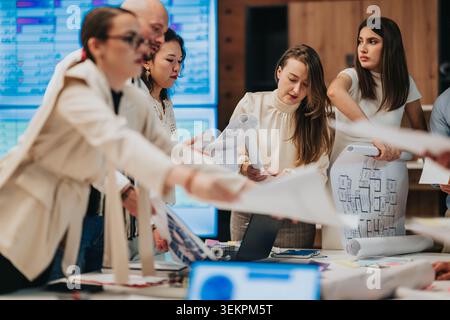 Business teammates reviewing architectural plans and documents during a collaborative office meeting Stock Photo