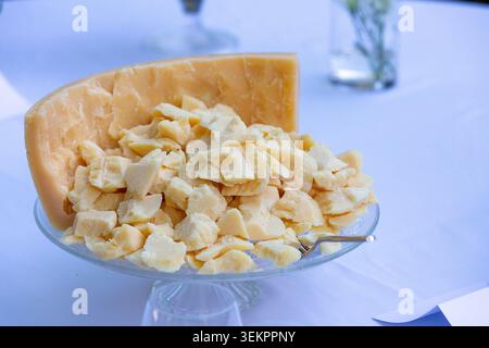 Parmesan cheese pieces and a large wedge resting on a glass cake stand Stock Photo