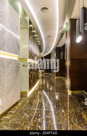 Abu Dhabi, UAE - November 27, 2025: Elegant corridor interior with black and gold marble floor, white marble walls, golden accents and curved LED ceil Stock Photo