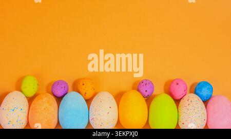 Beautiful multicoloured Easter eggs on a colourful background, vibrant coloured Easter egg treats on a pastel  flat lay celebrating the Easter holiday Stock Photo