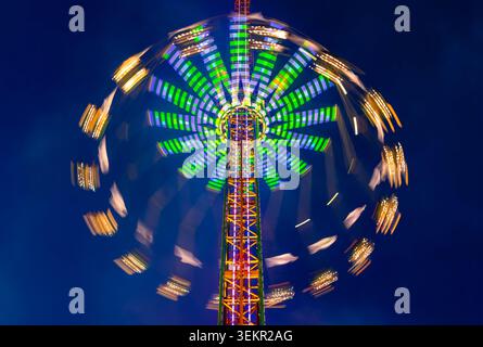 Merry-go-round or chairoplane with colorful led illumination at evening blue hour twilight. Magical circular light traces taken with long time exposur Stock Photo