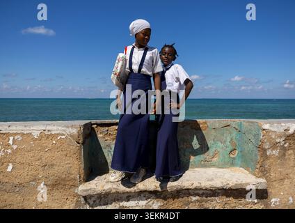 Girls standing on a bench in front of the sea, Nampula Province, Island of Mozambique, Mozambique Stock Photo
