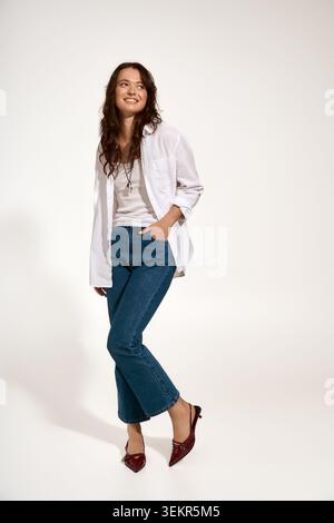 Young lady beams with joy while posing in trendy outfit, reflecting personal style and elegance. Stock Photo
