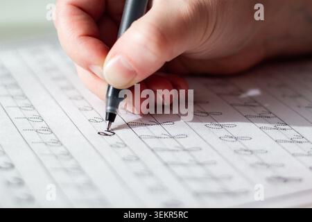 Person seated at desk deeply focused on writing in notebook. Physical engagement of motor skills Handwriting as brain training. Prevention of age rela Stock Photo