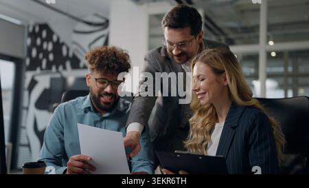 Three multiracial business managers working discussing documents statistic data reviewing papers talking multiethnic diversity businessmen men Stock Photo