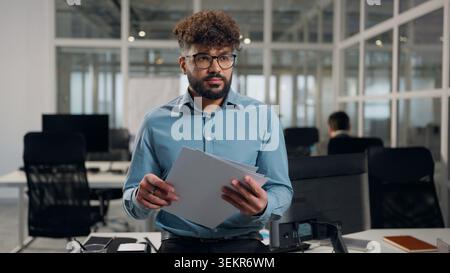 Hindu business man Arabian businessman holding analyzing papers documents profit results datum male guy analyst thinking review data stats financial Stock Photo