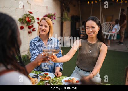 Multi ethnic women friends toasting with wine outdoor Stock Photo