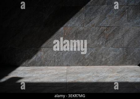 Minimalist architectural background with dramatic light and shadow contrast on marble texture.  Empty dark and light stone wall mockup space on a brig Stock Photo