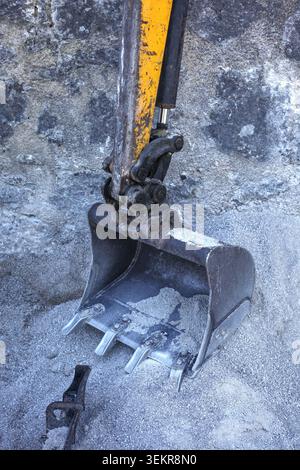 Small excavator metal bucket digging directly into a large pile of fine gravel at a site. Stock Photo