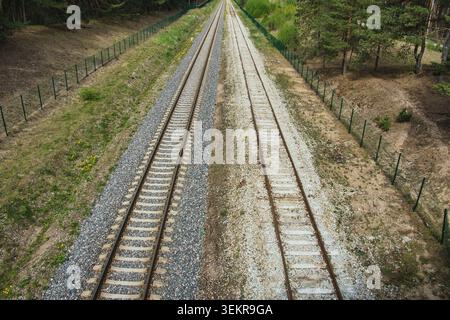 High angle view of parallel railway tracks stretching through a green landscape Stock Photo