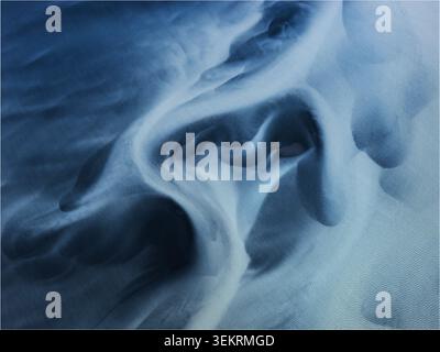 Aerial view of abstract patterns and textures of a glacial river delta with flowing blue water and silt in Thorshofn, Langanesbyggd, Iceland. Stock Photo