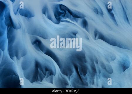 Aerial view of abstract glacial river patterns with blue sediment and swirling water textures in Thorshofn, Langanesbyggd, Iceland. Stock Photo