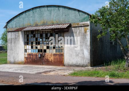 An abandoned warehouse sits in silence, its metal structure weathered and windows shattered. Left to decay over time, it serves as a stark reminder of Stock Photo