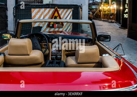 The interior dashboard and tan leather seats of a vintage red Mercedes-Benz SL convertible are visible on a street in Tirana, Albania. Stock Photo