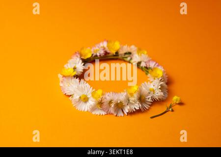 Midsummer wreath of wild flowers on orange background Stock Photo