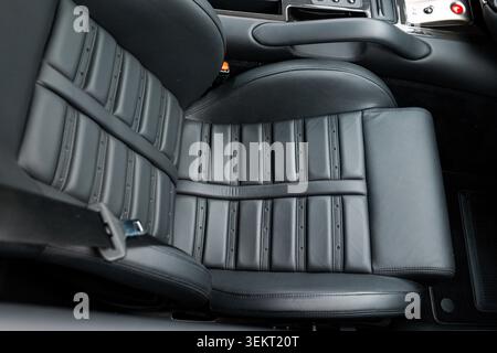 Detailed high-angle photograph focuses on the structured black leather bucket seat of a luxury sports car, featuring precision horizontal stitching, p Stock Photo