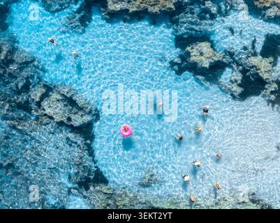 Aerial top down view of people swimming in clear turquoise sea Stock Photo