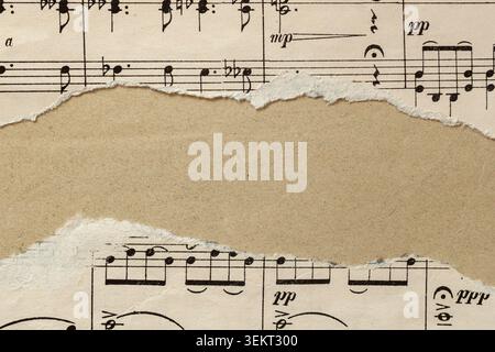 Torn sheet music paper frames empty center for scrapbooking collage, journal design, and craft projects. Natural background with sheet music, craft pa Stock Photo