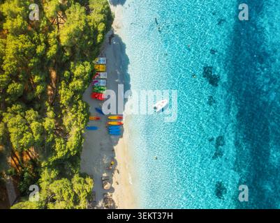 Aerial top down view of sandy beach with green trees, boat, sea Stock Photo