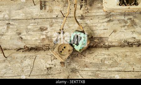 Old electrical outlet and switch on a dirty wooden wall Stock Photo