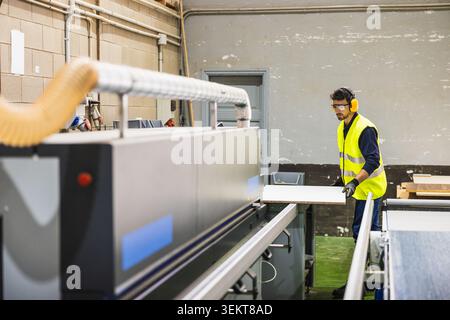 Woodworker operating industrial machine in manufacturing workshop Stock Photo