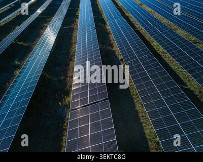 Aerial view of solar panels creating geometric lines at a photovoltaic power plant for clean energy production. Stock Photo