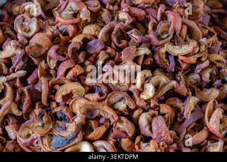 High angle texture shot of a large pile of dehydrated brown and red apple slices sold at a traditional bazaar in Bishkek, Kyrgyzstan. Stock Photo