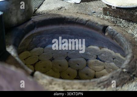 Looking inside a hot circular stone tandoor oven with rows of traditional round flatbread dough stuck to the inside walls in Leh, India. Stock Photo