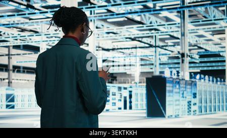 Writing code, tablet and female programmer walking in data center, compiling software patches. Running programming script, device application and African american woman in server hub, camera A Stock Photo