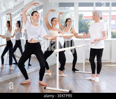 Sporty woman performing demi plie during group barre fitness workout Stock Photo