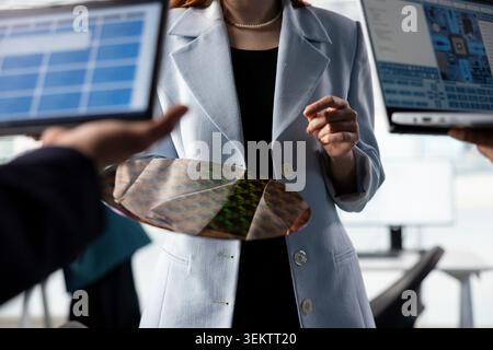 Doing quality inspection, silicon wafer close up and engineering team in PCB factory RD lab. Examining intricate circuit patterns, semiconductor substrates and teamworking colleagues in office Stock Photo