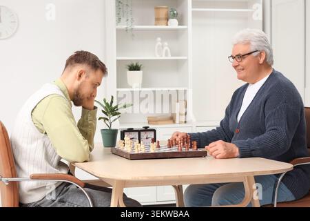 Senior man and his son playing chess at home Stock Photo