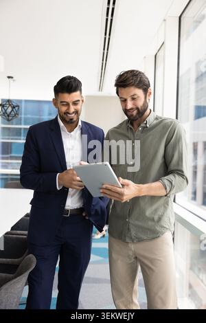 Two multiethnic businessmen collaborating, working together using digital tablet Stock Photo