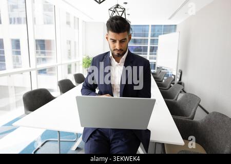 Focused Indian businessman working remotely using modern laptop in office Stock Photo