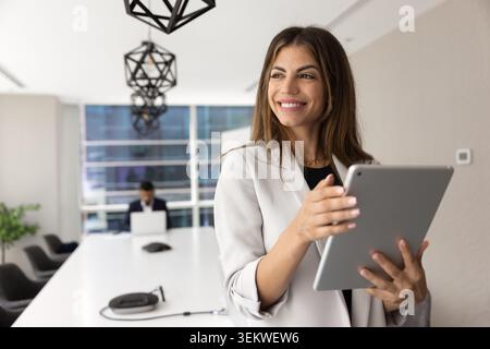 Confident Hispanic businesswoman working on digital tablet Stock Photo