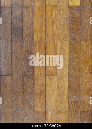 A top-down full-frame view of a worn wooden parquet floor showing various brown shades, natural grain patterns, and visible surface scratches from lon Stock Photo
