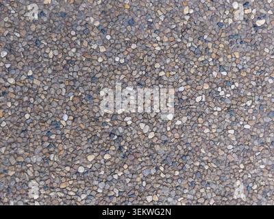 Close-up view of exposed aggregate concrete featuring multicolored pebbles embedded in cement, showcasing rough texture and durable decorative outdoor Stock Photo
