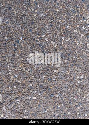 A high-angle, vertical shot of an exposed aggregate concrete surface. Features a dense, textured pattern of small multicolor river stones, gravel, and Stock Photo